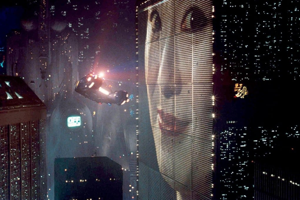 Image from Blade runner of flying car next to a building with a digital board displaying woman's face